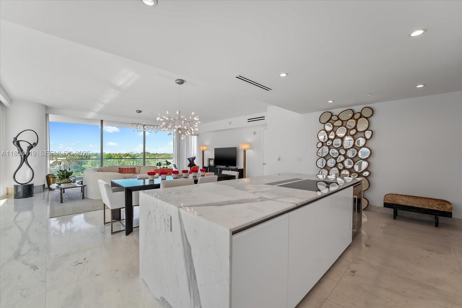 A modern open-concept kitchen and dining area features a marble island and floor-to-ceiling windows — 10201 Collins Ave # 511, Bal Harbour FL 33154, BAL HARBOUR, FL