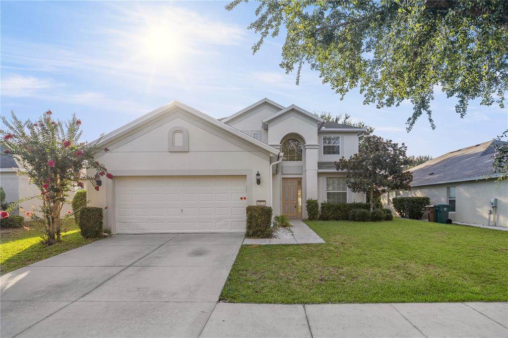 A two-story suburban house with a beige stucco exterior, a two-car garage, and a lawn — 4073 SW 47TH COURT, OCALA, FL