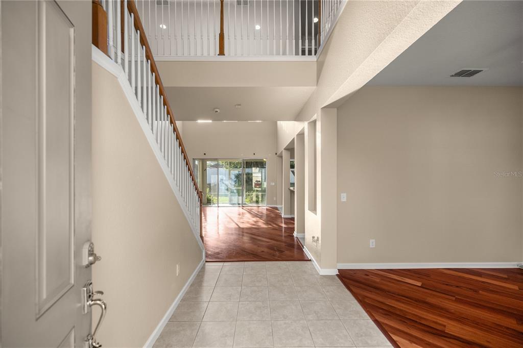 An entryway with tile flooring leads to a living area with hardwood floors and stairs — 4073 SW 47TH COURT, OCALA, FL