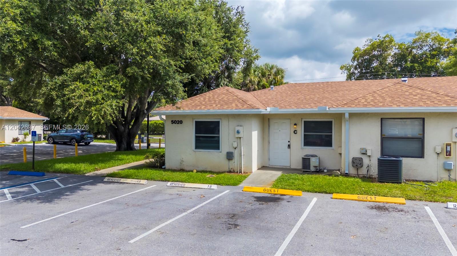 A single-story building with a tan exterior, a brown shingled roof, and designated parking spaces — 5020 Sanctuary Way # C, West Palm Beach FL 33417, WEST PALM BEACH, FL