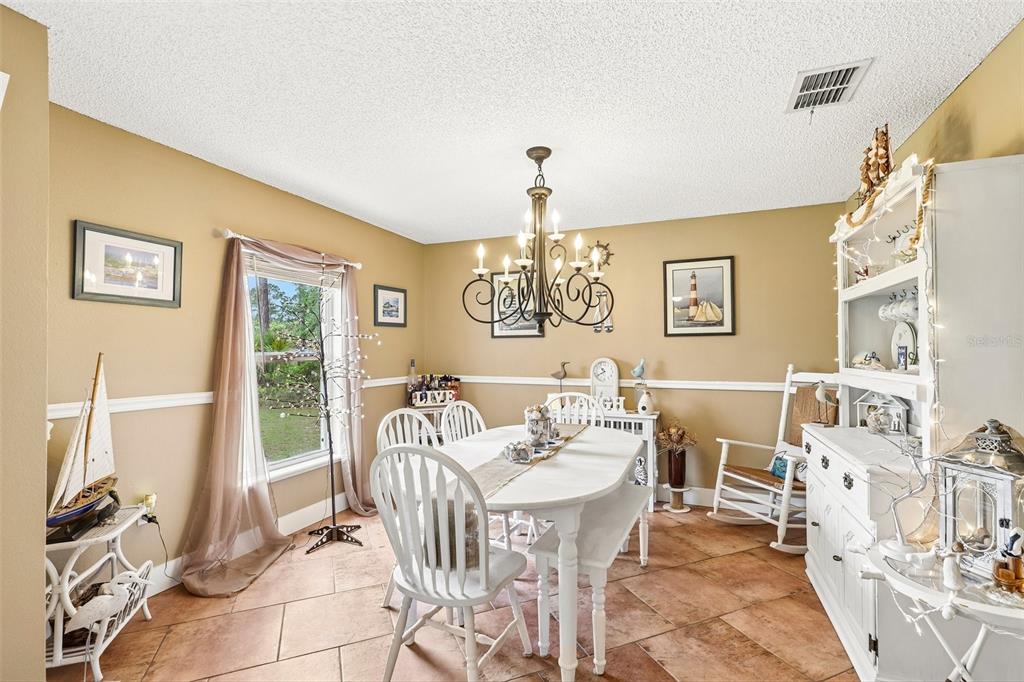 A dining room with a white table, chairs, chandelier, and a white hutch on tile floors — 17 PINELL LANE, PALM COAST, FL