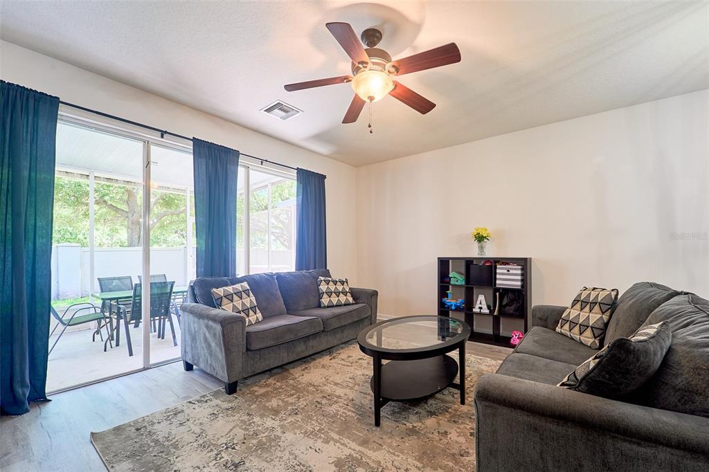 A living room features two gray sofas, a glass coffee table, and sliding glass doors — 5014 POND RIDGE ROAD, RIVERVIEW, FL