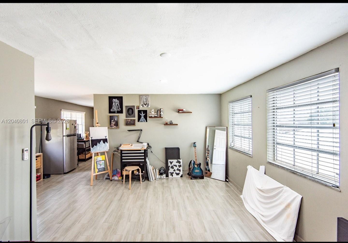 A small kitchen features white cabinets, a wood-look backsplash, and a portable kitchen island — 359 W 12th St # 3, Hialeah FL 33010, HIALEAH, FL