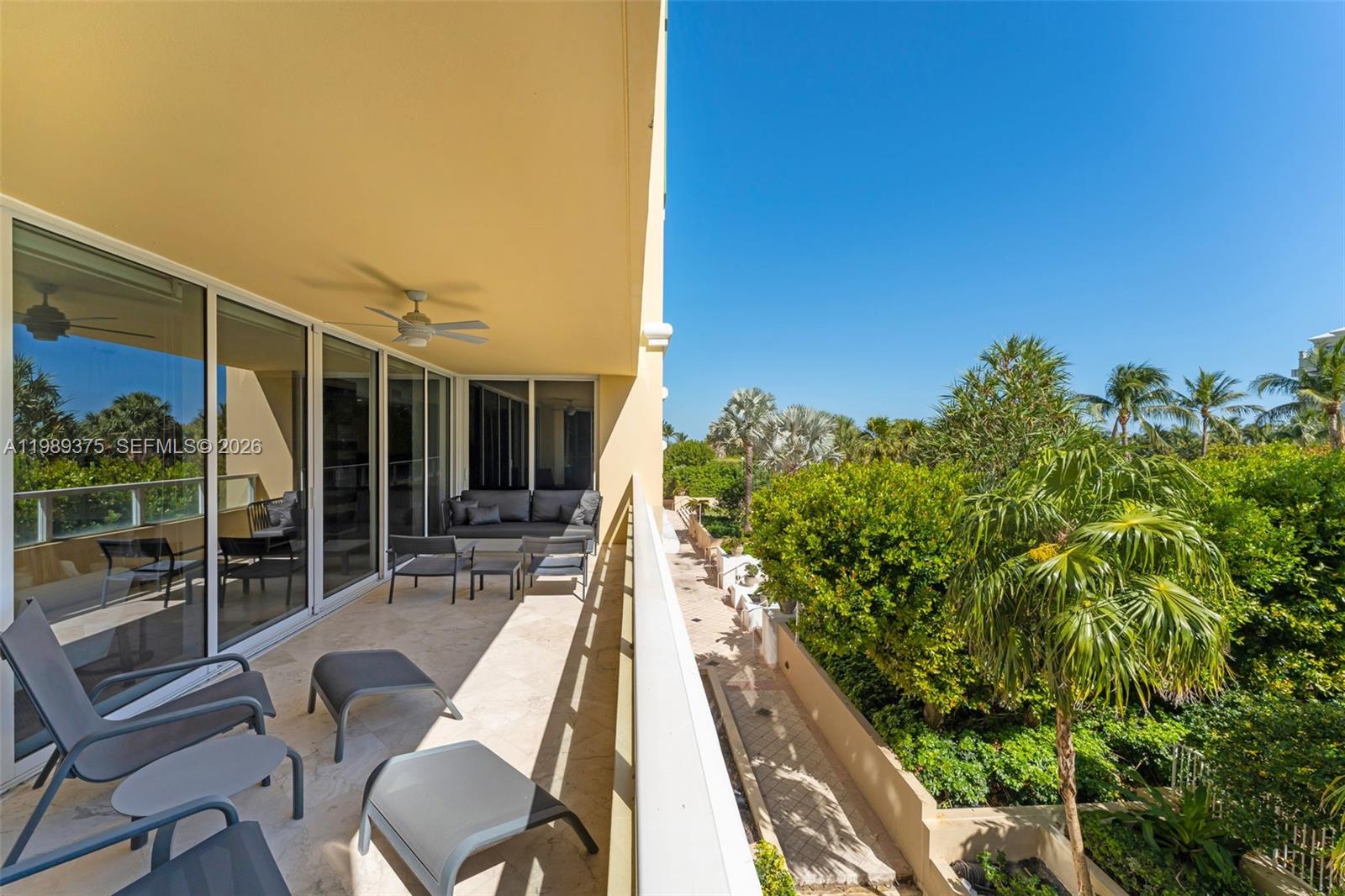 A spacious balcony features tile flooring, outdoor seating, and a view of lush greenery — 430 Grand Bay Dr # 307, Key Biscayne FL 33149, KEY BISCAYNE, FL