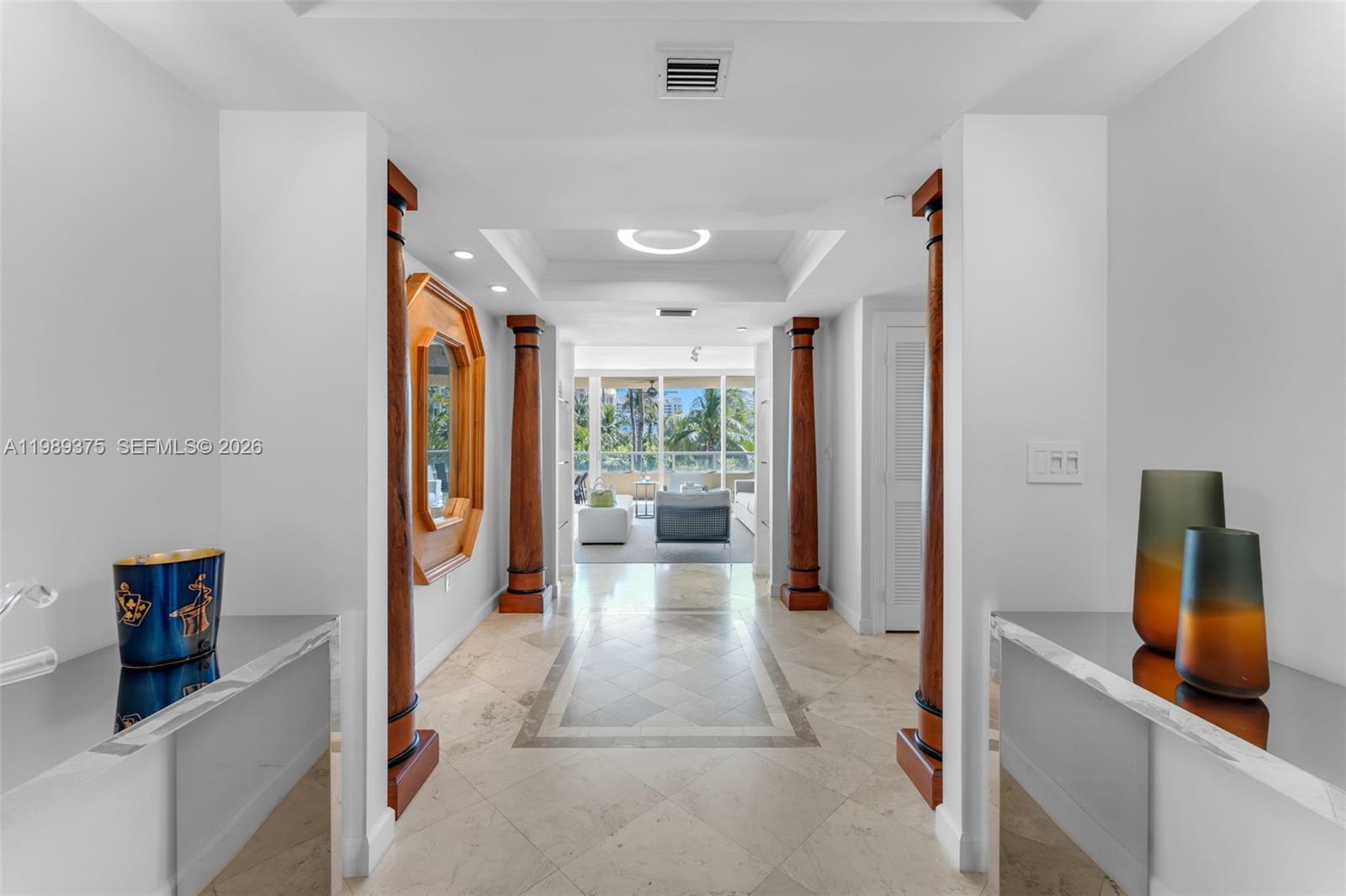 A bright hallway features decorative wooden columns, tile flooring, and a view of a balcony — 430 Grand Bay Dr # 307, Key Biscayne FL 33149, KEY BISCAYNE, FL