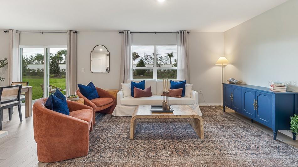 A living room features a white sofa, two orange armchairs, and a blue sideboard — 12419 HOPSCOTCH AVENUE, PARRISH, FL