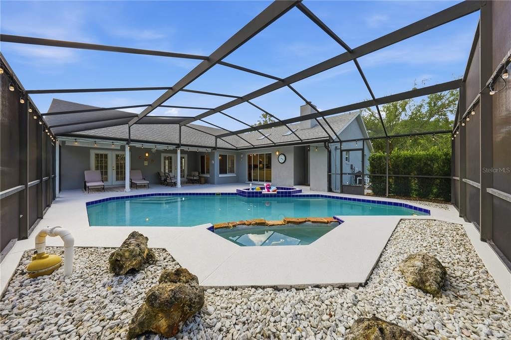 A screened-in patio features a swimming pool, a hot tub, and a gravel garden area — 2622 MAYWOOD STREET, EUSTIS, FL