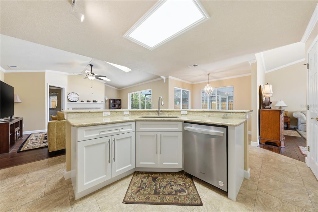 A kitchen island with white cabinets, a stainless steel dishwasher, and a granite countertop — 2622 MAYWOOD STREET, EUSTIS, FL