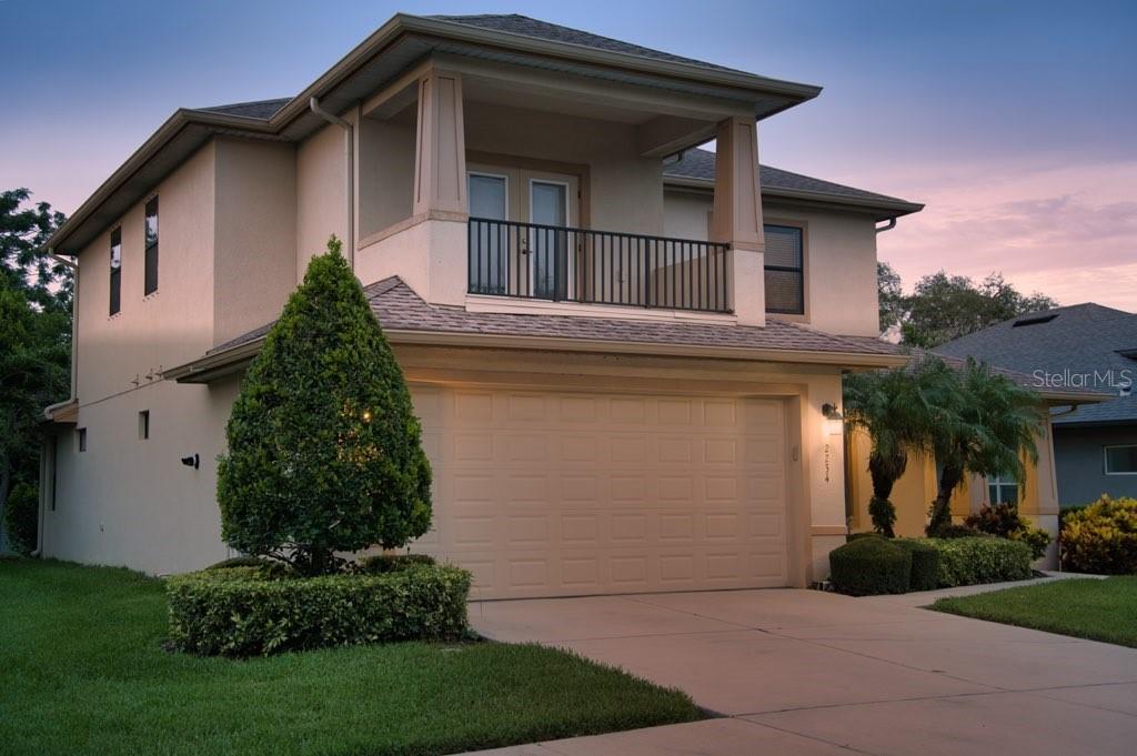 A two-story house with a beige stucco exterior, a two-car garage, and a second-floor balcony — 2234 HIGHWOOD COURT, DUNEDIN, FL