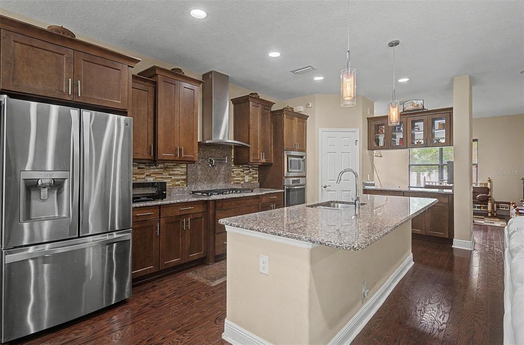 A kitchen features wood cabinets, granite countertops, stainless steel appliances, and a central island — 2234 HIGHWOOD COURT, DUNEDIN, FL