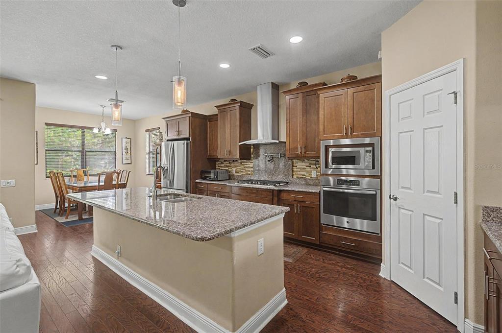 A kitchen features a granite-topped island, stainless steel appliances, and dark wood cabinetry — 2234 HIGHWOOD COURT, DUNEDIN, FL