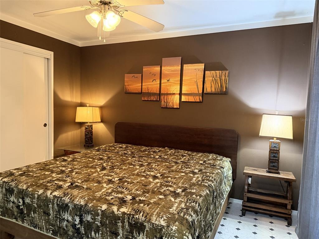 A bedroom features a bed with a camouflage comforter, two lamps, and a multi-panel wall art — 628 NE 816 AVENUE, OLD TOWN, FL