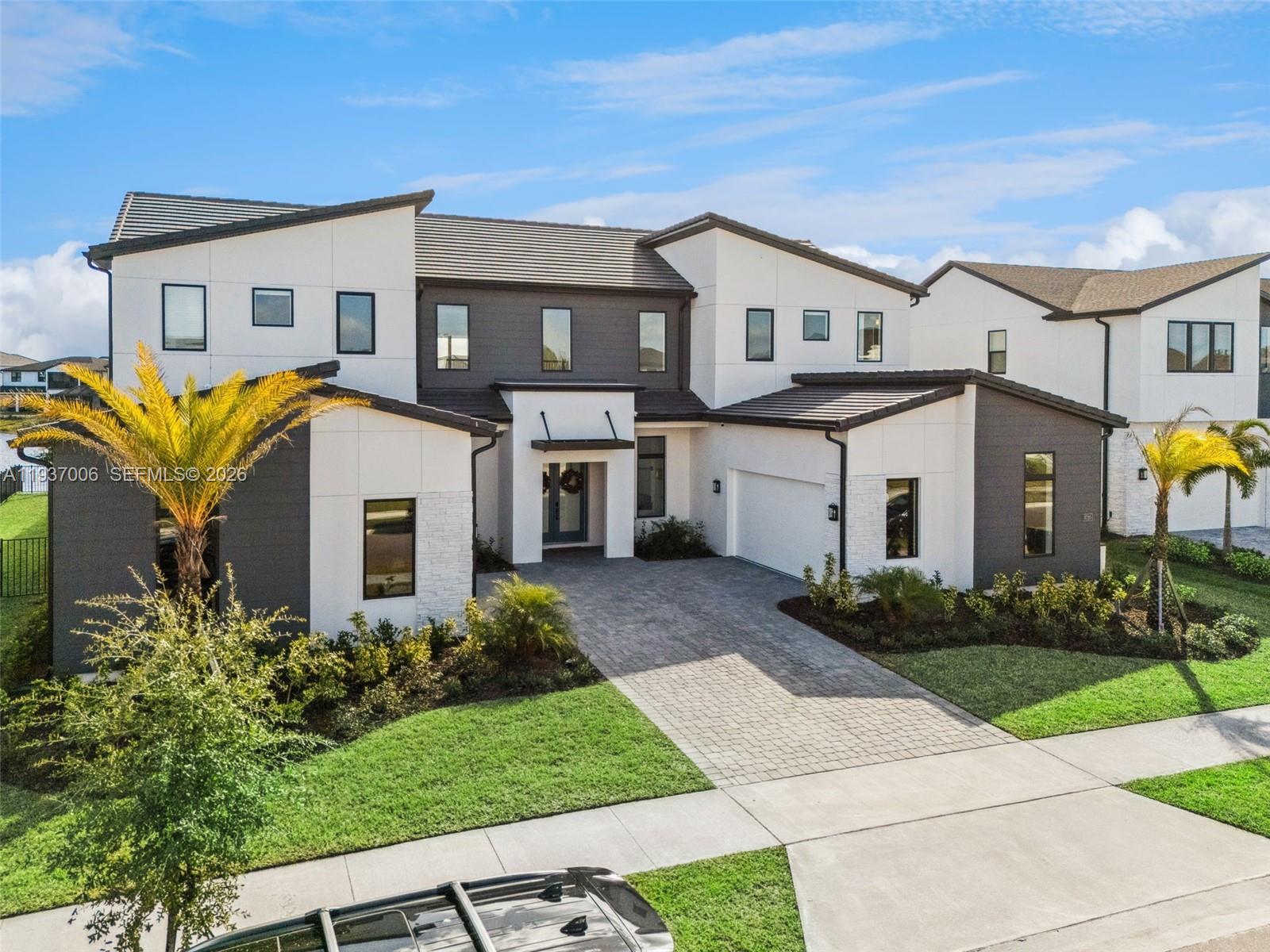 A two-story modern house features a paved driveway, white and dark gray siding, and palm trees — 9720 Laurel Berry Drive, Orlando FL 32827, ORLANDO, FL