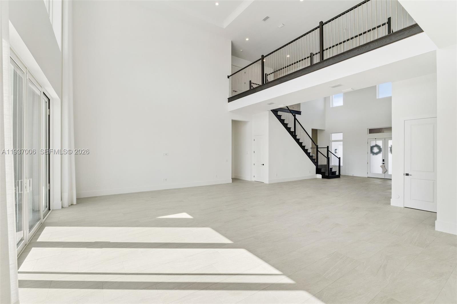 A spacious, high-ceilinged living area features light tile flooring, a staircase, and a balcony railing — 9720 Laurel Berry Drive, Orlando FL 32827, ORLANDO, FL