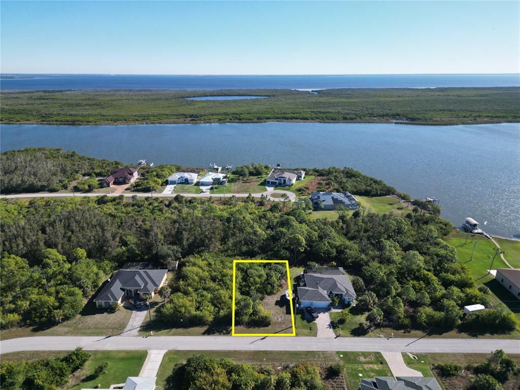 An aerial view shows a vacant, rectangular lot outlined in yellow between two residential houses — 9558 SHELBURNE CIRCLE, PORT CHARLOTTE, FL