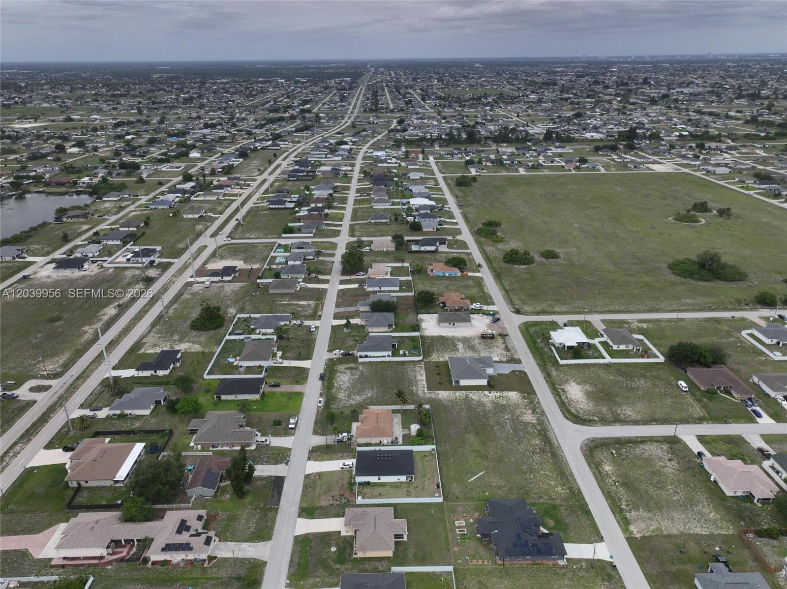 An aerial view shows a suburban neighborhood with scattered houses, paved roads, and vacant lots — 530 NW 23RD TER, Cape Coral FL 33993, CAPE CORAL, FL