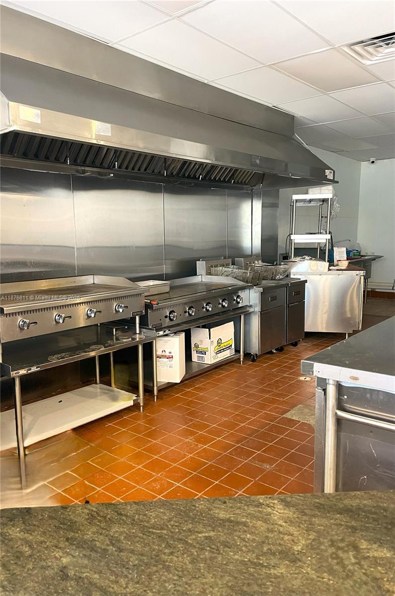 A commercial kitchen features stainless steel cooking equipment, a ventilation hood, and tiled flooring — 550 Piedmont Ave, GA 30308, GA