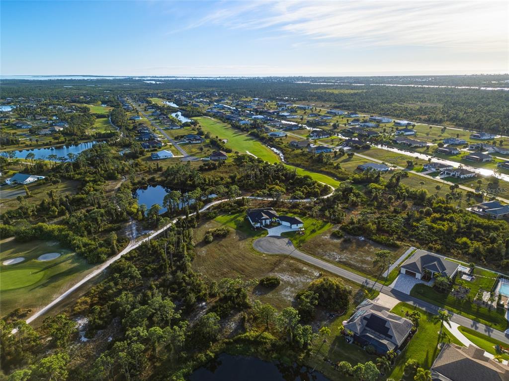 An aerial view shows houses situated near a golf course, ponds, and natural vegetation — 14 PINE VALLEY ROAD, ROTONDA WEST, FL