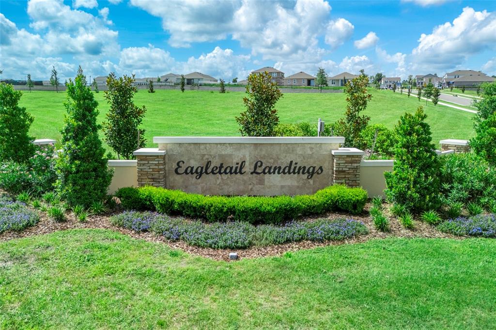 A stone monument sign for Eagletail Landings sits in front of a large grassy field — 27456 BLACK KITE AVENUE, HOWEY IN THE HILLS, FL