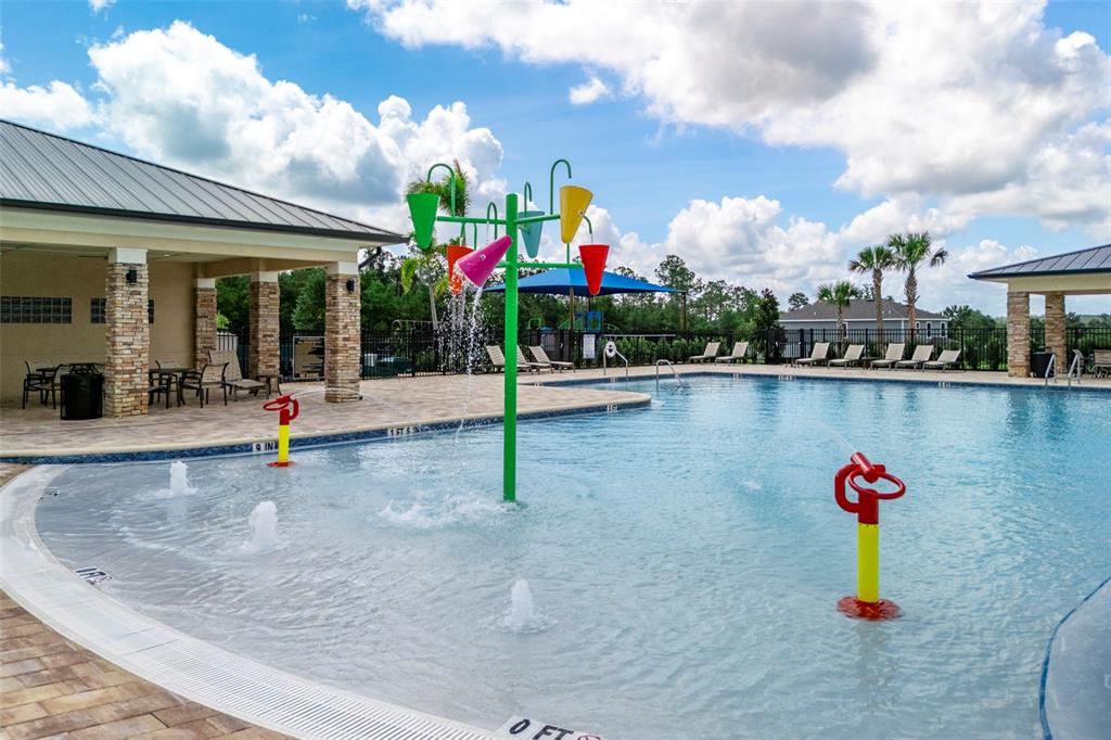 A shallow swimming pool features a central water play structure with colorful dumping buckets — 27456 BLACK KITE AVENUE, HOWEY IN THE HILLS, FL