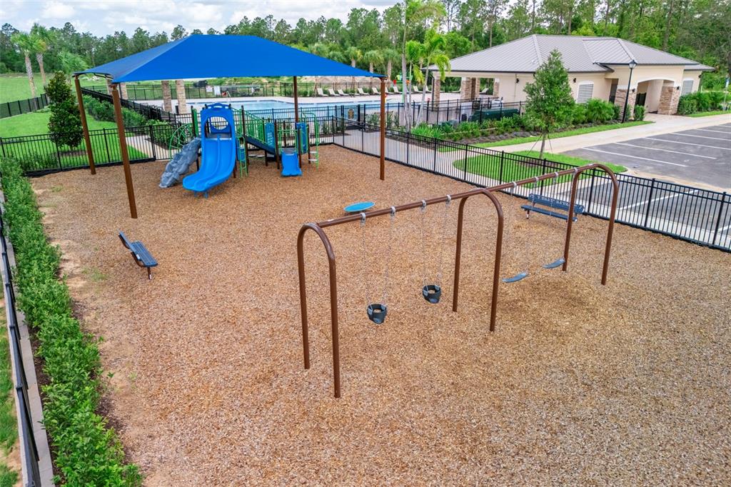 An aerial view of a fenced playground featuring a swing set and a covered slide — 27456 BLACK KITE AVENUE, HOWEY IN THE HILLS, FL