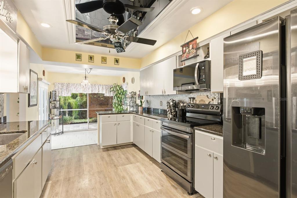 A patio with a table, chairs, and umbrella overlooks a screened-in swimming pool — 8218 MELISSA COURT, HUDSON, FL
