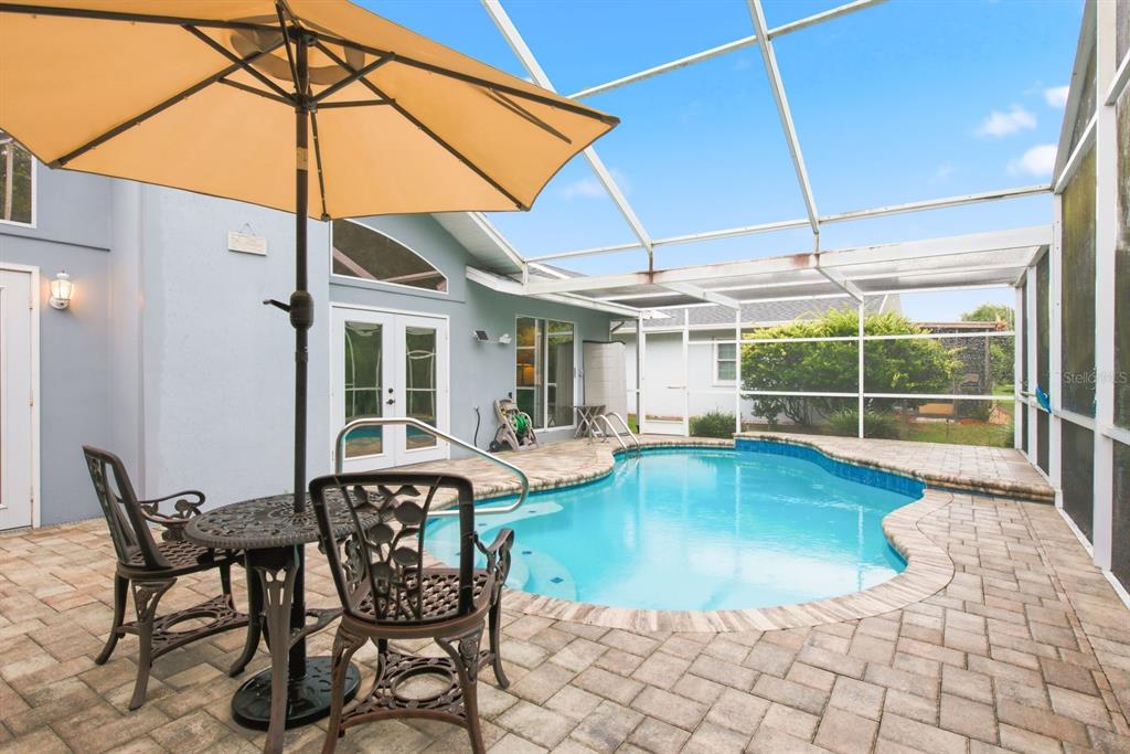 A living room features a fireplace, a pool table, tile flooring, and glass doors to a pool — 8218 MELISSA COURT, HUDSON, FL