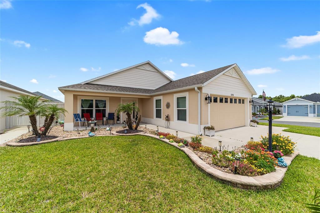 A single-story house with a beige exterior, a two-car garage, and a landscaped front yard — 6576 MERRILL LANE, THE VILLAGES, FL