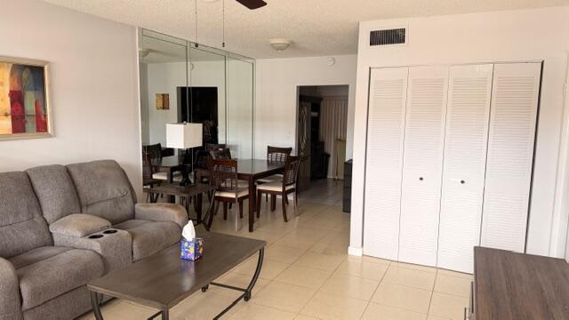 A living room with a gray sofa, dining area, mirrored wall, and white closet doors — 5 Abbey Lane # 104, Delray Beach FL 33446, DELRAY BEACH, FL