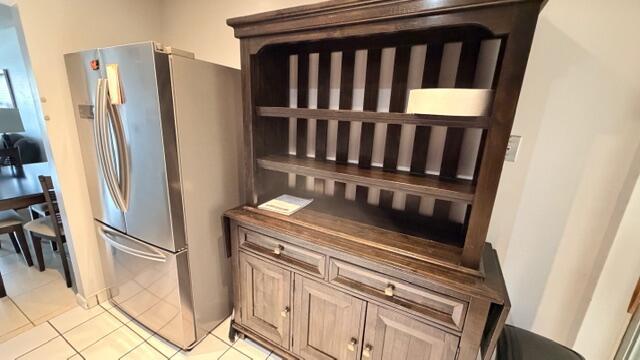 A stainless steel refrigerator stands next to a dark wood hutch in a kitchen — 5 Abbey Lane # 104, Delray Beach FL 33446, DELRAY BEACH, FL