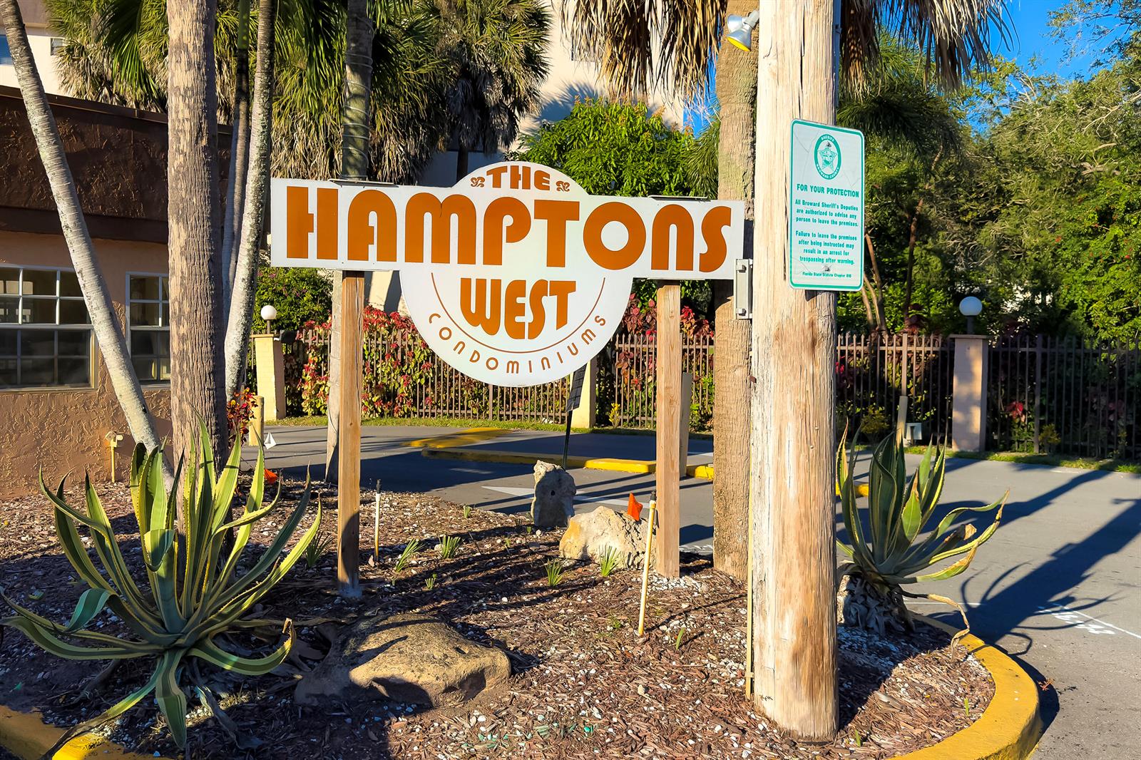 A sign for The Hamptons West Condominium stands in a landscaped area with palm trees — 8030 Hampton Boulevard # 502, North Lauderdale FL 33068, NORTH LAUDERDALE, FL