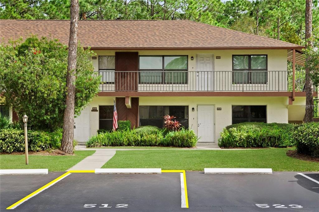 A two-story apartment building with a balcony, parking spaces, and landscaping in front — 108 LACOSTA LANE UNIT 512, DAYTONA BEACH, FL