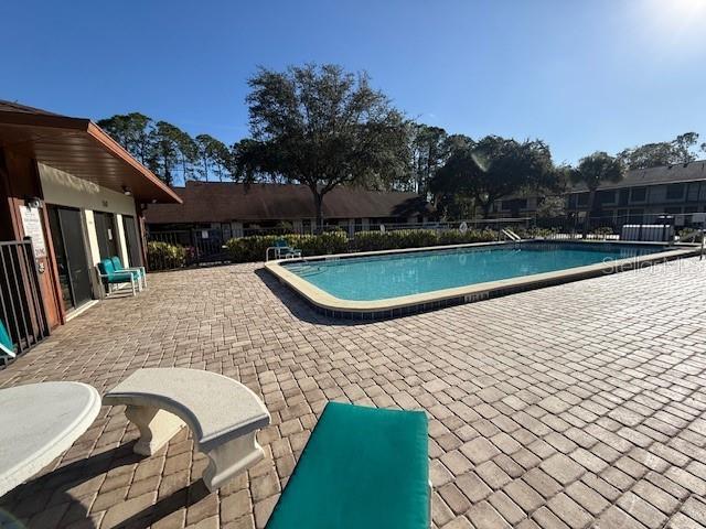 A swimming pool sits on a paved patio next to a building with a porch — 108 LACOSTA LANE UNIT 512, DAYTONA BEACH, FL