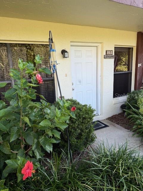 A white front door with a house number is surrounded by landscaping and a bird feeder — 108 LACOSTA LANE UNIT 512, DAYTONA BEACH, FL