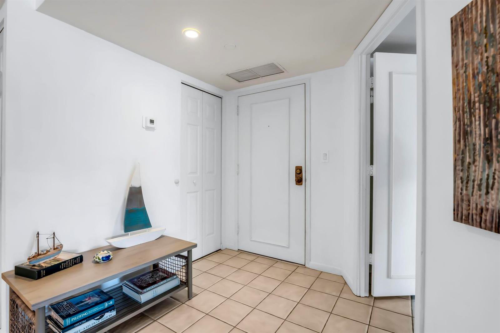 An entryway features a tiled floor, a wooden console table, and a white door — 4301 N Ocean Boulevard # A206, Boca Raton FL 33431, BOCA RATON, FL
