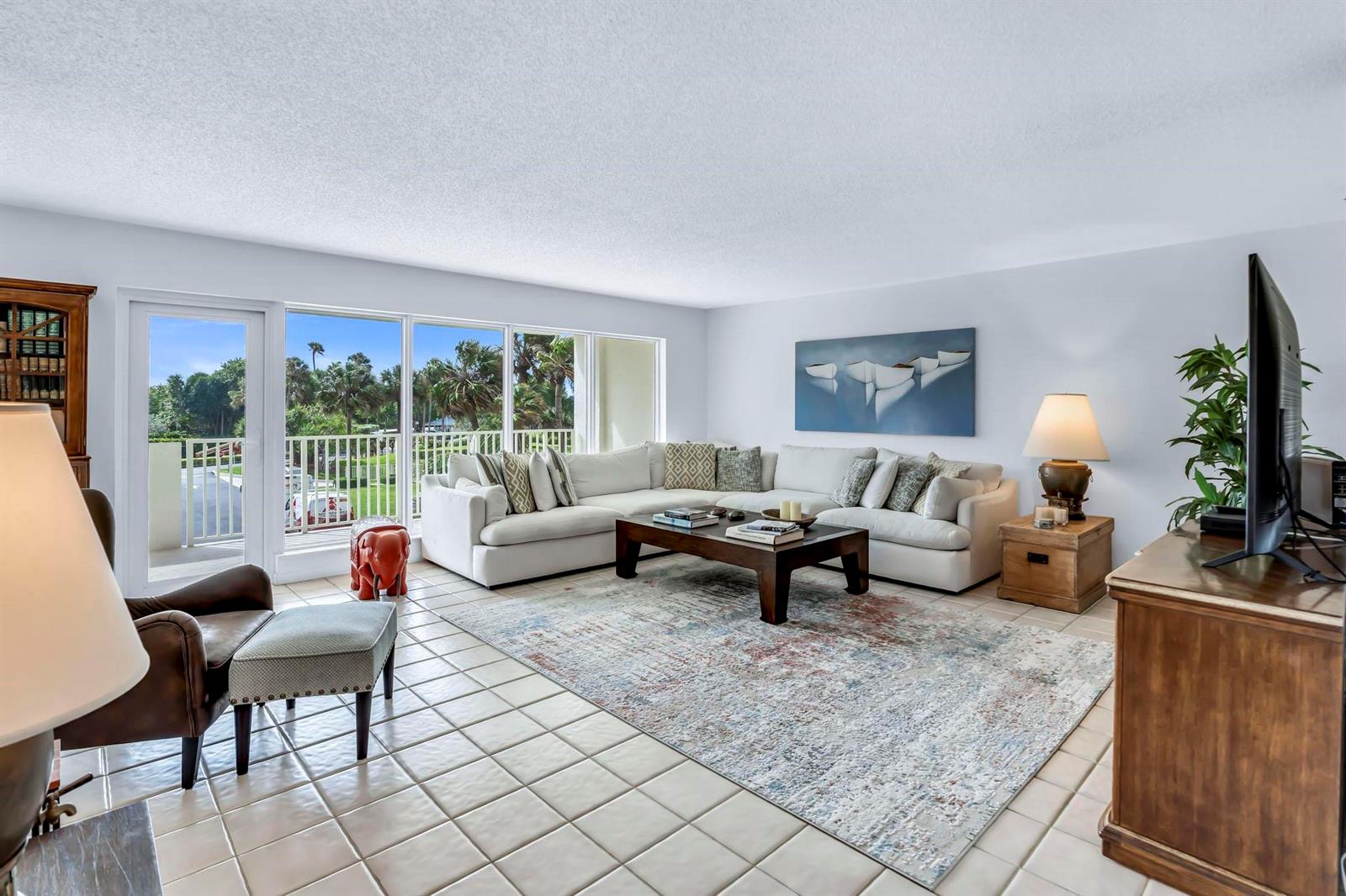 A living room features a white sectional sofa, a patterned area rug, and floor-to-ceiling windows — 4301 N Ocean Boulevard # A206, Boca Raton FL 33431, BOCA RATON, FL
