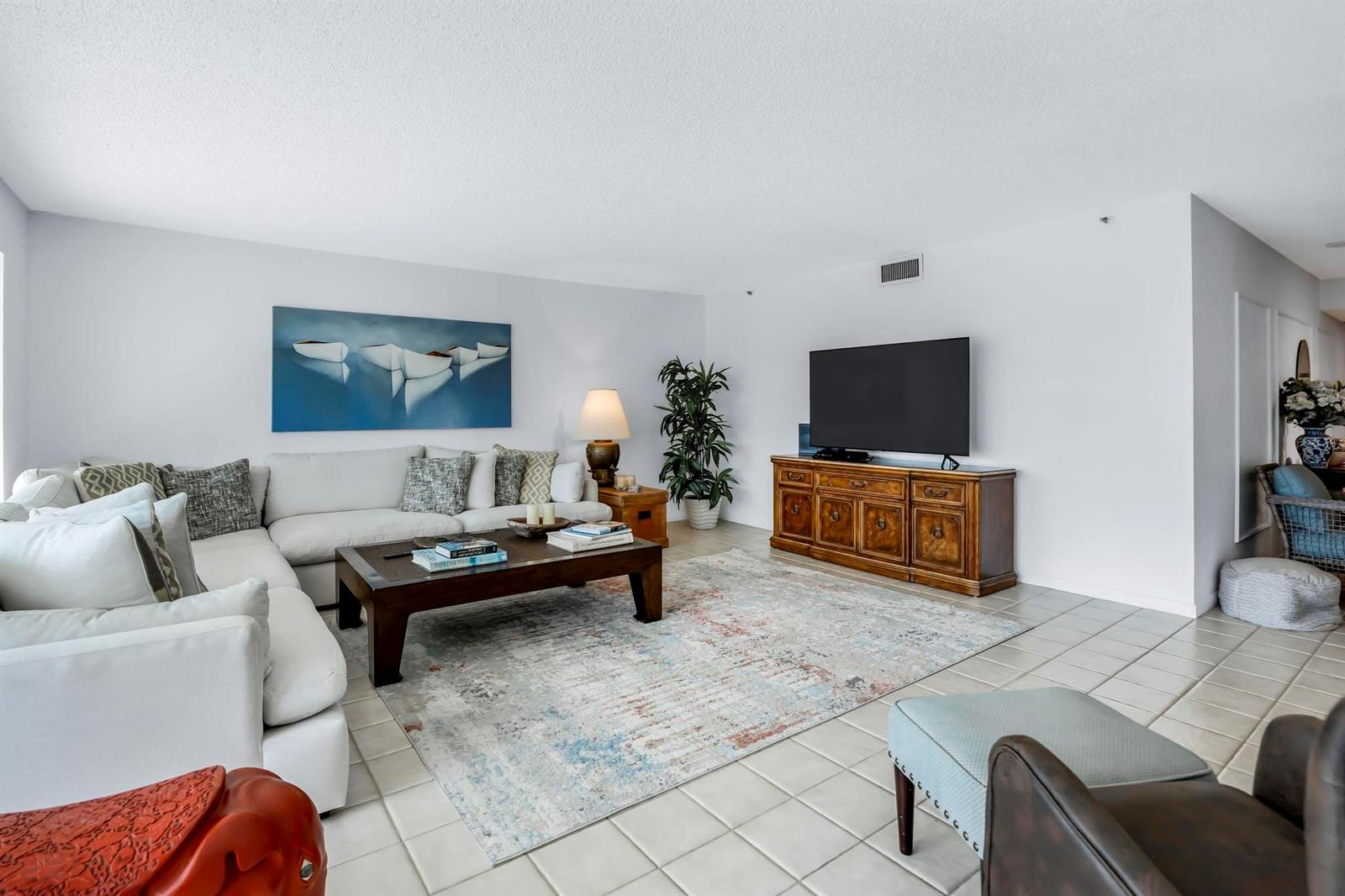 A living room features a white sectional sofa, a wooden coffee table, and a television console — 4301 N Ocean Boulevard # A206, Boca Raton FL 33431, BOCA RATON, FL
