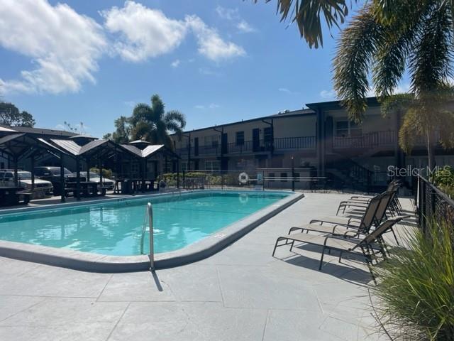 A swimming pool with lounge chairs sits in front of a multi-story apartment building — 675 INDIAN ROCKS ROAD N UNIT 209D, BELLEAIR BLUFFS, FL