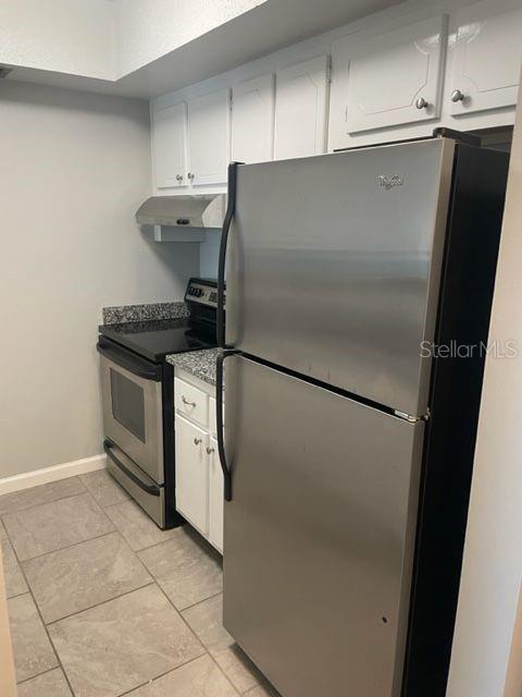 A kitchen features white cabinets, stainless steel appliances, granite countertops, and light-colored tile flooring — 675 INDIAN ROCKS ROAD N UNIT 209D, BELLEAIR BLUFFS, FL