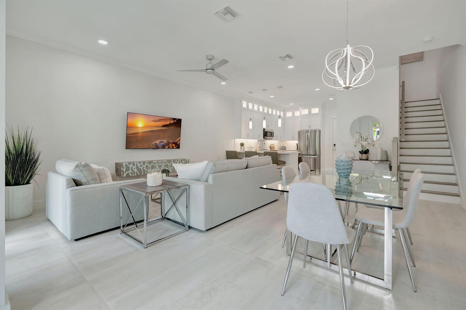 An open-concept living and dining area features light-colored furniture, a glass table, and white cabinetry — 4695 SE Manatee Way, Stuart FL 34997, STUART, FL