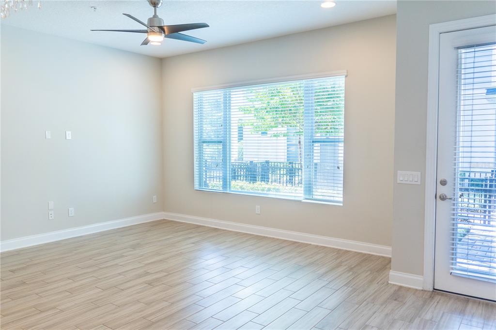 An empty room with light wood-look tile flooring, a ceiling fan, and large windows — 1011 LYCHEE COURT, LAKE MARY, FL