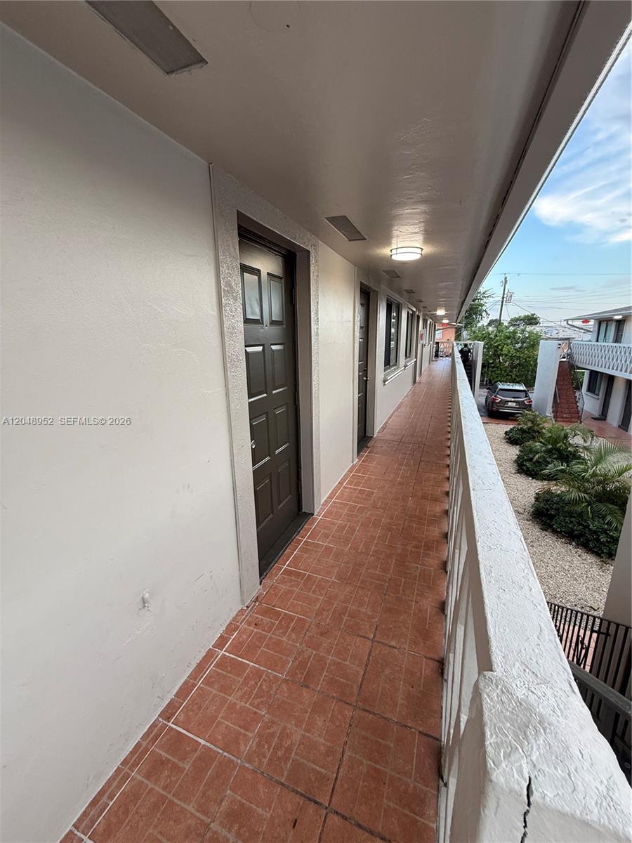 An outdoor walkway with tiled flooring leads past several dark doors along a building exterior — 654 W 29th St # 4, Hialeah FL 33012, HIALEAH, FL