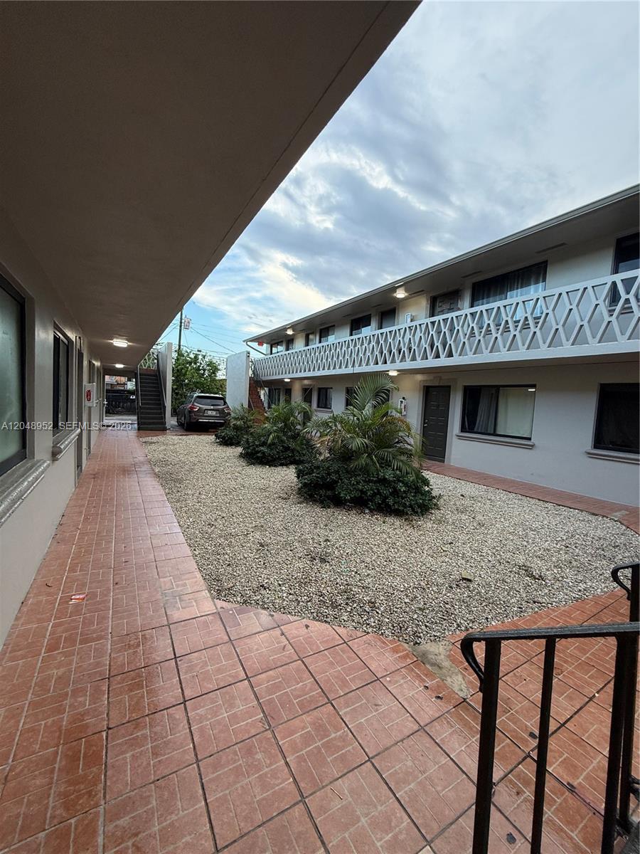 An exterior view of a two-story apartment building with a tiled walkway and gravel courtyard — 654 W 29th St # 4, Hialeah FL 33012, HIALEAH, FL