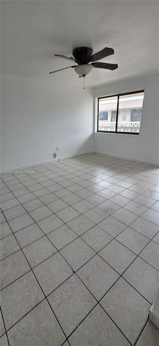 An empty room features white walls, a ceiling fan, and light-colored square floor tiles — 654 W 29th St # 4, Hialeah FL 33012, HIALEAH, FL