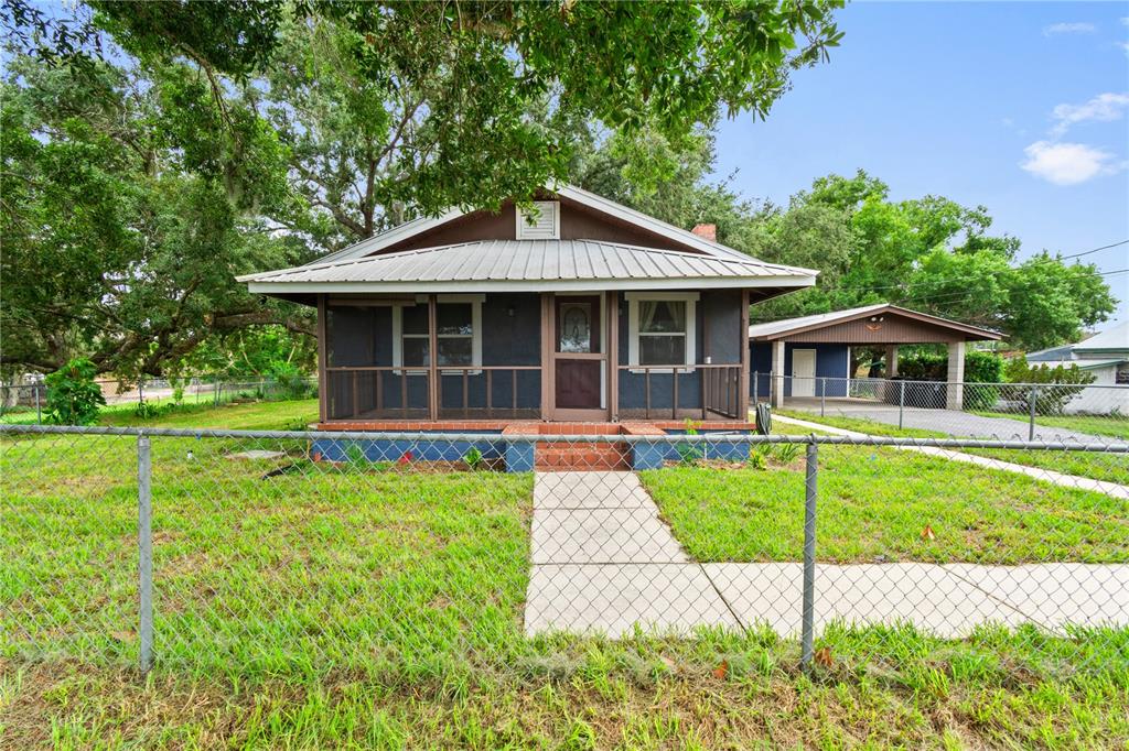 A dark blue house with a metal roof and a screened front porch — 30 E 8TH STREET, FROSTPROOF, FL