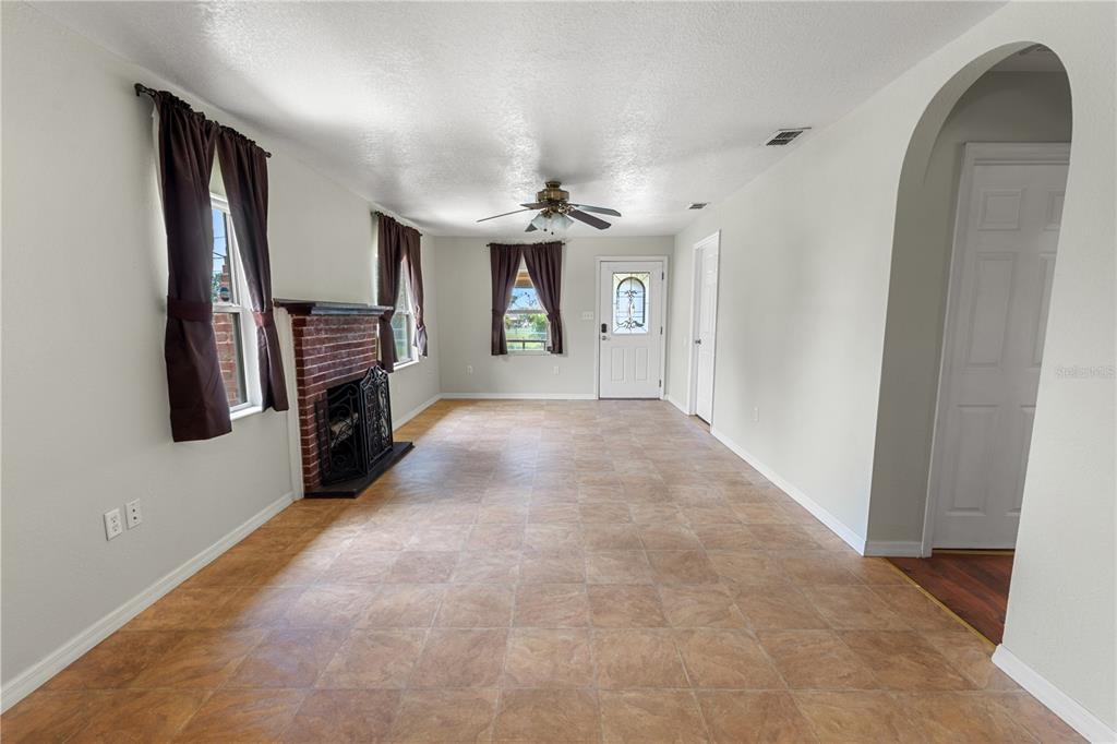 A living room features tile flooring, a brick fireplace, and a ceiling fan — 30 E 8TH STREET, FROSTPROOF, FL