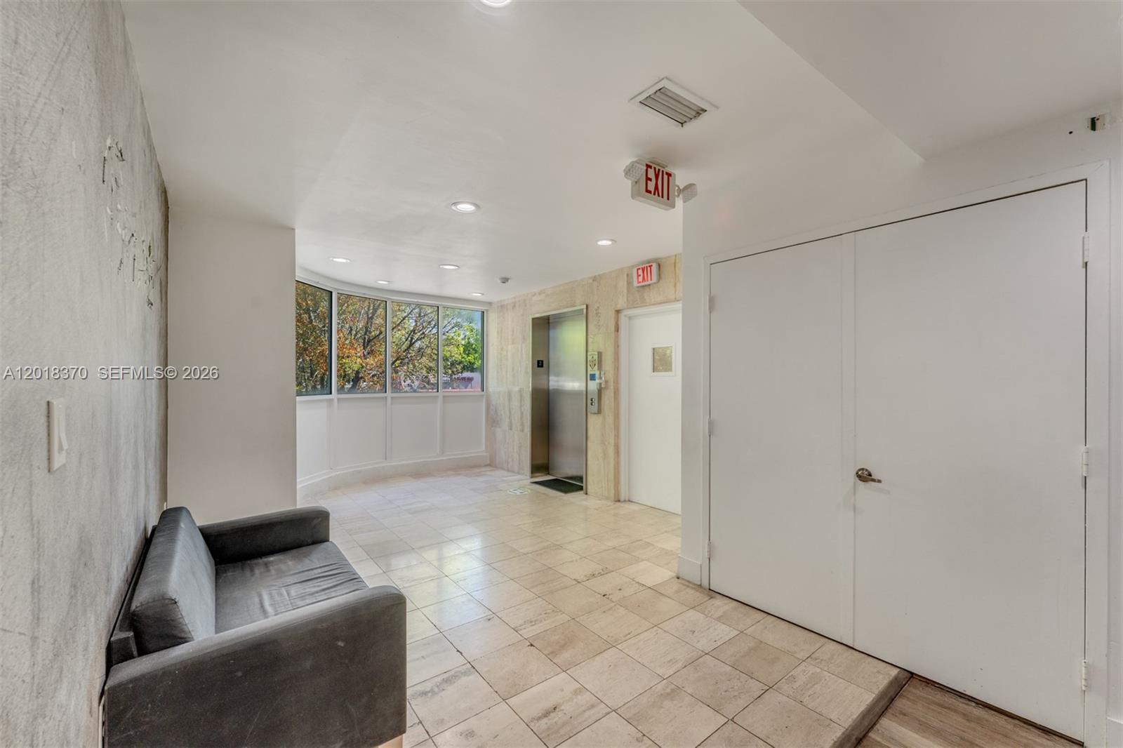 A lobby area features a gray sofa, tile flooring, an elevator, and large windows — 1378 SW 22nd St # 2, Miami FL 33145, MIAMI, FL
