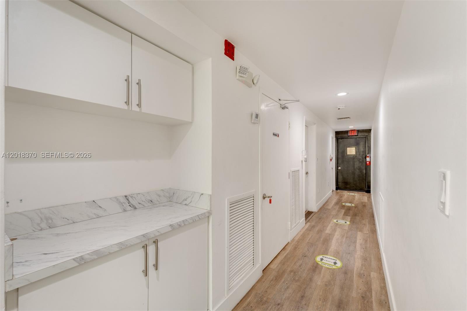 A hallway features white cabinetry with marble countertops, wood-look flooring, and an exit door — 1378 SW 22nd St # 2, Miami FL 33145, MIAMI, FL