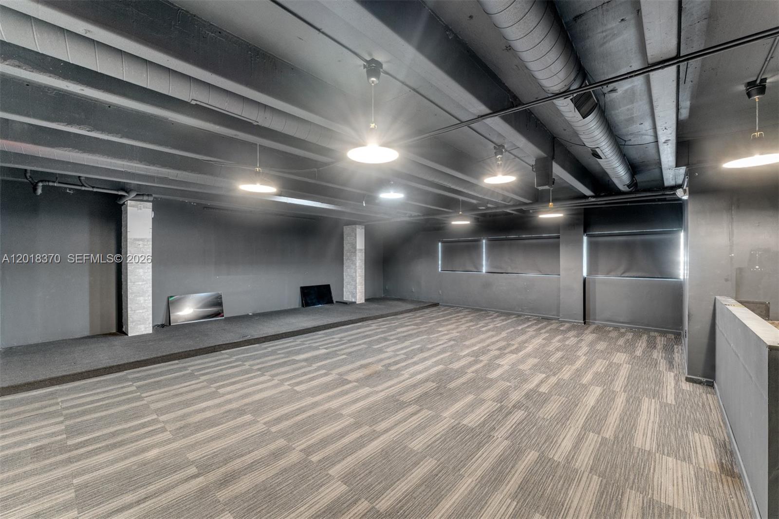 An empty room features gray walls, a raised carpeted platform, and exposed industrial ceiling ducts — 1378 SW 22nd St # 2, Miami FL 33145, MIAMI, FL