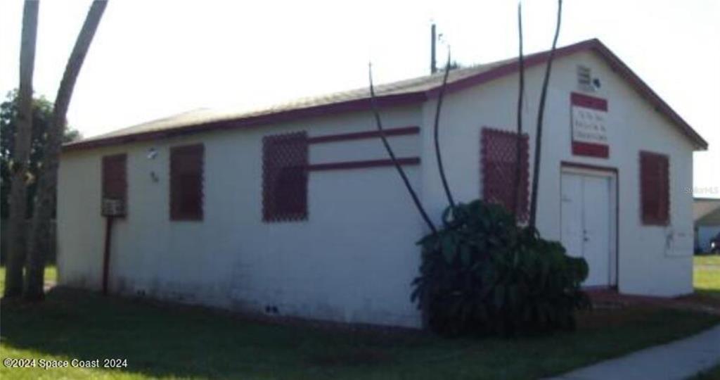 A single-story building with white stucco walls, red trim, and barred windows — 929 S DELEON AVENUE, TITUSVILLE, FL